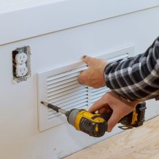 Man is installing the wall cover ventilation vent maintenance repair works renovation in the new home before installing
